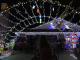 “A house decorated with an extensive display of Christmas lights, including hanging stars, colorful bulbs, and strings of white and yellow lights forming an archway over the driveway. Festive inflatables and cut-outs, such as cartoon characters in holiday outfits, sit on one side. Several people stand or sit in the foreground, looking toward the brightly lit house at night.”