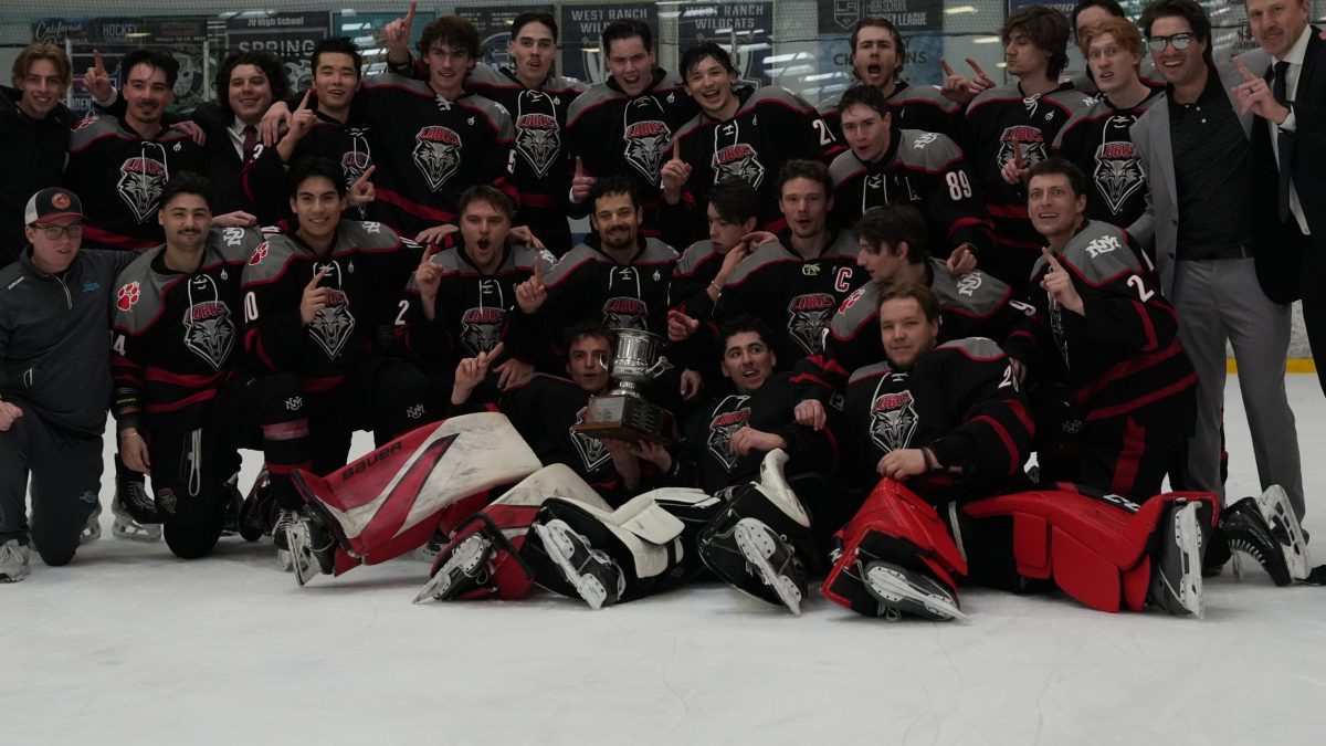 University of New Mexico Lobos in black and red uniforms poses on the ice with a championship trophy, celebrating at The Cube rink after a playoff win