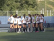 COC Wonen's soccer team wearing white jerseys and dark shorts huddles together on a green turf field during a sunny day.