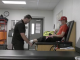 A sports trainer evaluates a young athlete’s leg on a treatment table in an athletic training room, surrounded by medical equipment and supplies.